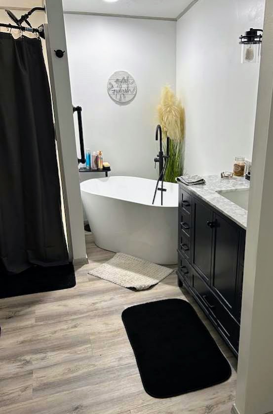 Modern bathroom with freestanding white tub, black faucet, and black vanity with marble countertop