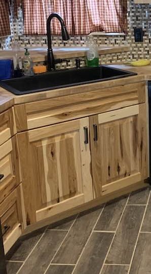 Rustic kitchen with natural wood cabinets and drawers, a matte black sink and faucet, and a mosaic tile backsplash.
