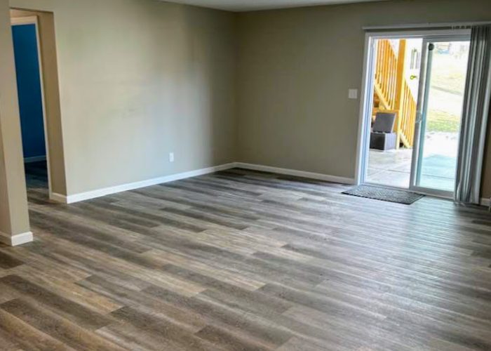 Empty living room with newly installed vinyl plank flooring and neutral wall colors