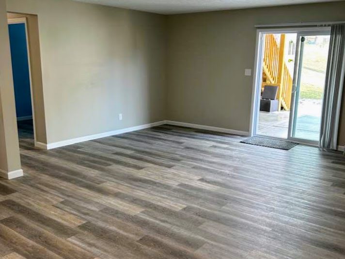 Empty living room with newly installed vinyl plank flooring and neutral wall colors