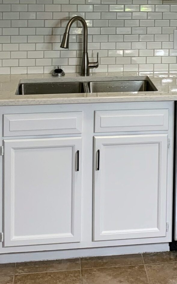 Modern kitchen with white shaker-style cabinets, a double stainless steel sink, brushed nickel faucet, and glossy white subway tile backsplash.